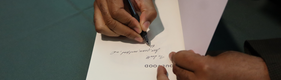 Photograph of an author signing a copy of a book during an event at Franklin College