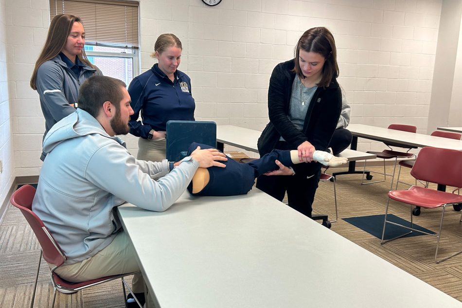 Photograph of people using a shoulder joint reduction trainer at Franklin College.